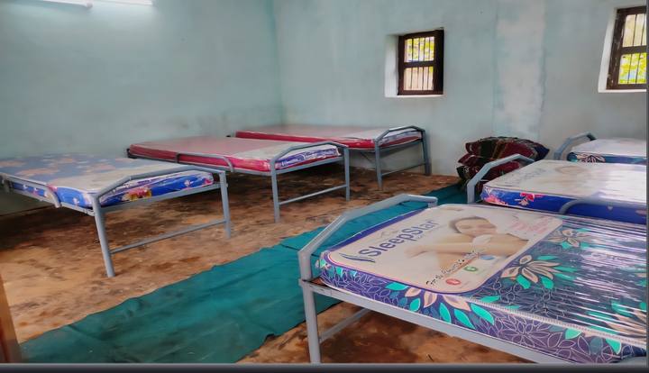 Metal beds with new mattresses in a pale blue dormitory room
