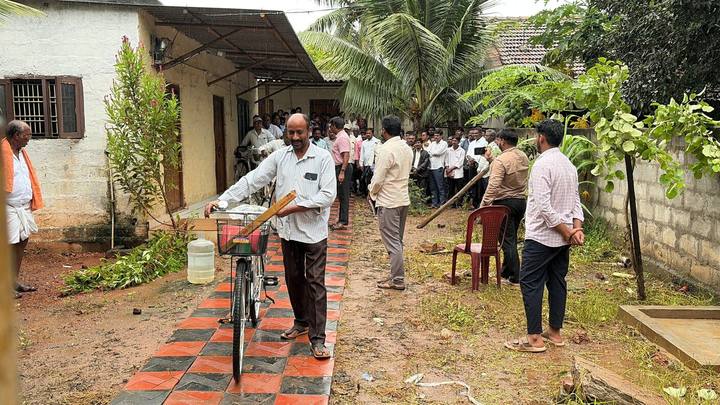 A man wheeling a new bicycle along a tiled path while others watch
