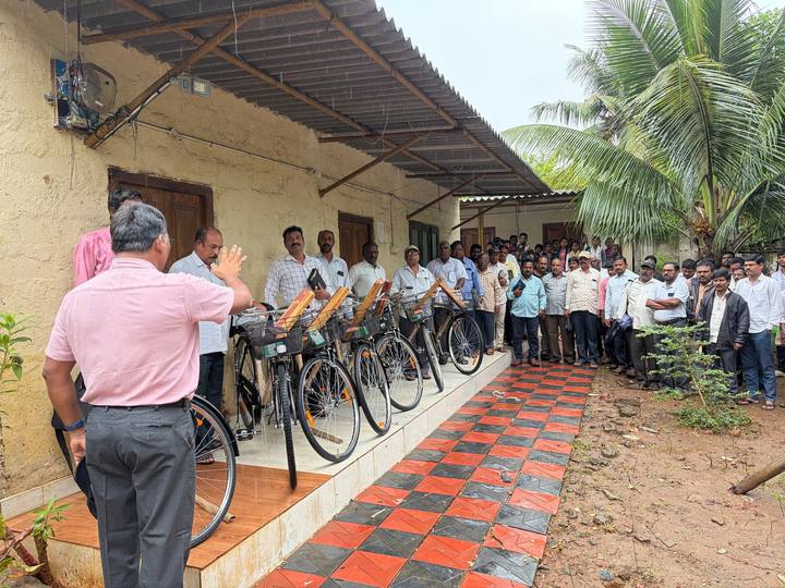 New bicycles with gift boxes lined up on a porch as a crowd of pastors looks on