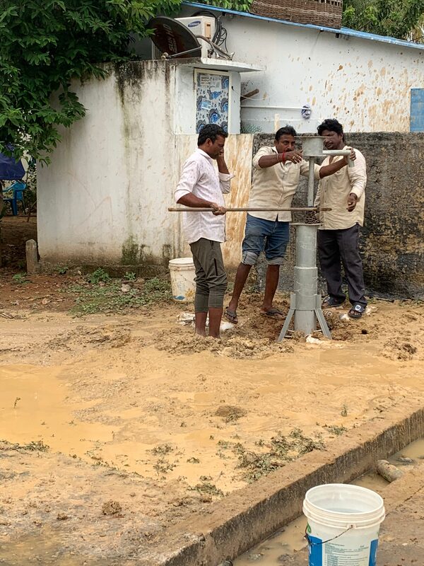 Men installing a hand pump in a yard