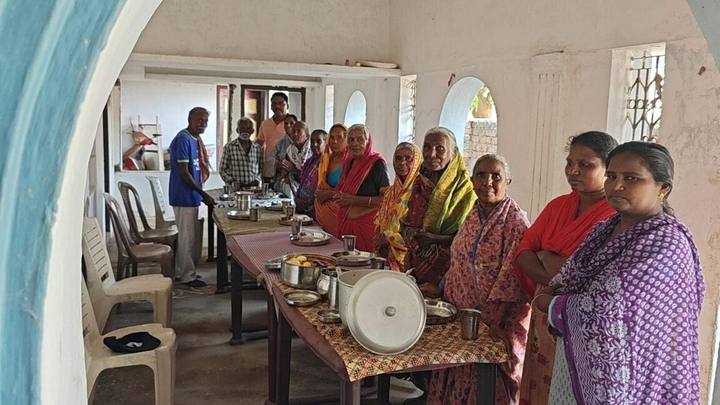 Women standing beside a long table set for a meal